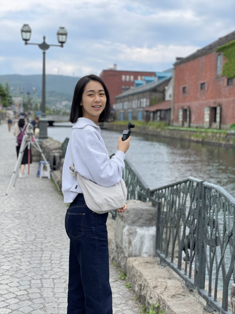Sunny Huang is standing on a brick pathway, slightly turned towards the camera.