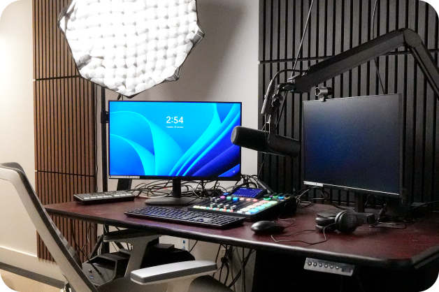 A podcast studio with a desk, microphone and a computer on the windows screen.