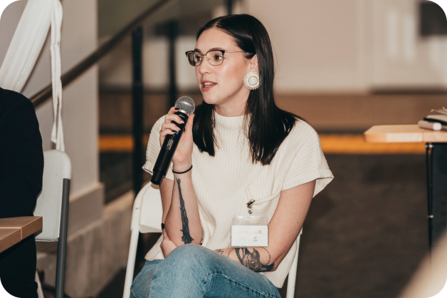 develop-digital-ai-skills-benefits-1-woman presenting An Ampere staff presenting at an all staff event. She has a microphone in her hand and is looking out into an audience.