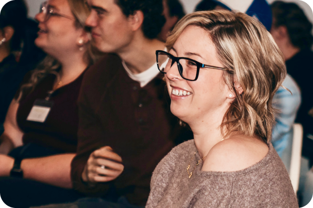 develop-digital-ai-skills-benefits-2-workshop participant A woman is smiling and facing forward, others are blurred behind her.