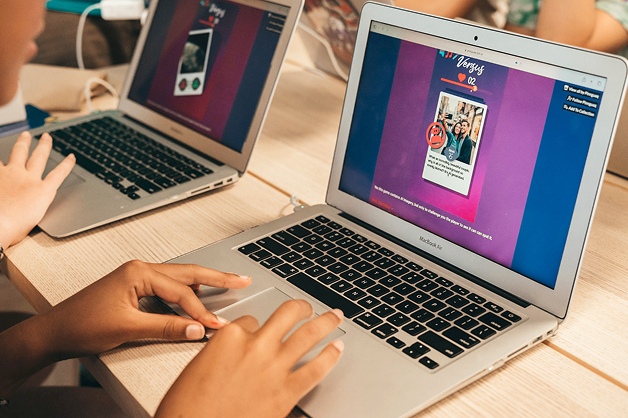Two laptops sitting on a table, a program is running on the screen and the users are using the keypad.