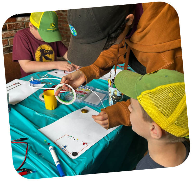 Two learners are working together to create a circuit. They have the circuit tape unraveled and are putting it on paper. 