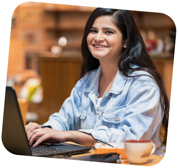 small-business-support-programs-1-girl on computer A young adult is sitting at a computer, looking over towards the camera and smiling.