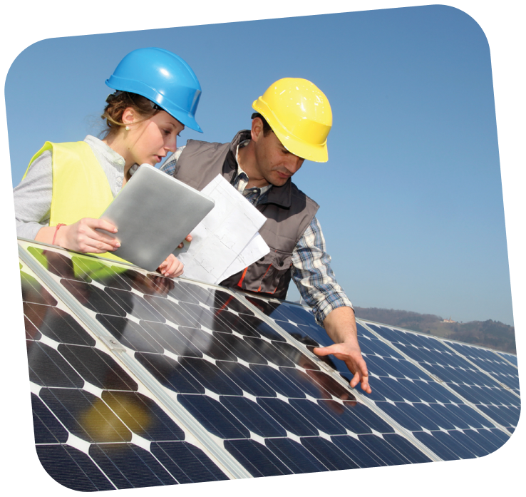 small-business-support-programs-2-solar power technicians Two workers wearing hard hats and reflective vests are leaning over a solar panel. The sky is bright blue behind them.
