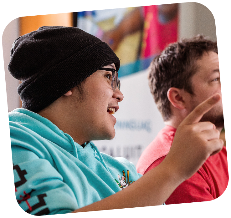 A close up of a teenager pointing forwards, acting very engaged in a conversation.