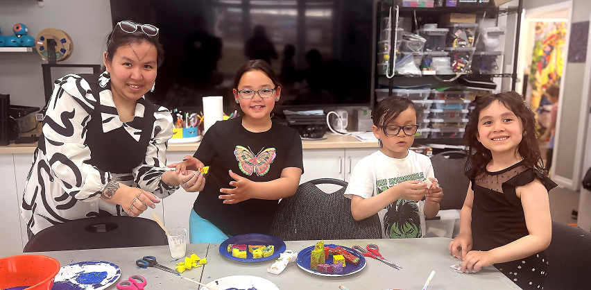 Three young learners and an adult looking towards the camera and smiling. 