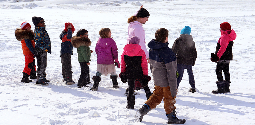 A group of students in winter gear, walking outside in the snow.