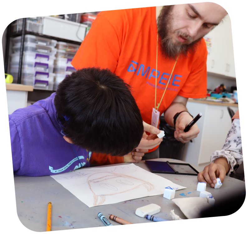 A STEAM educator wearing an orange Ampere shirt is helping a student with a drawing.
