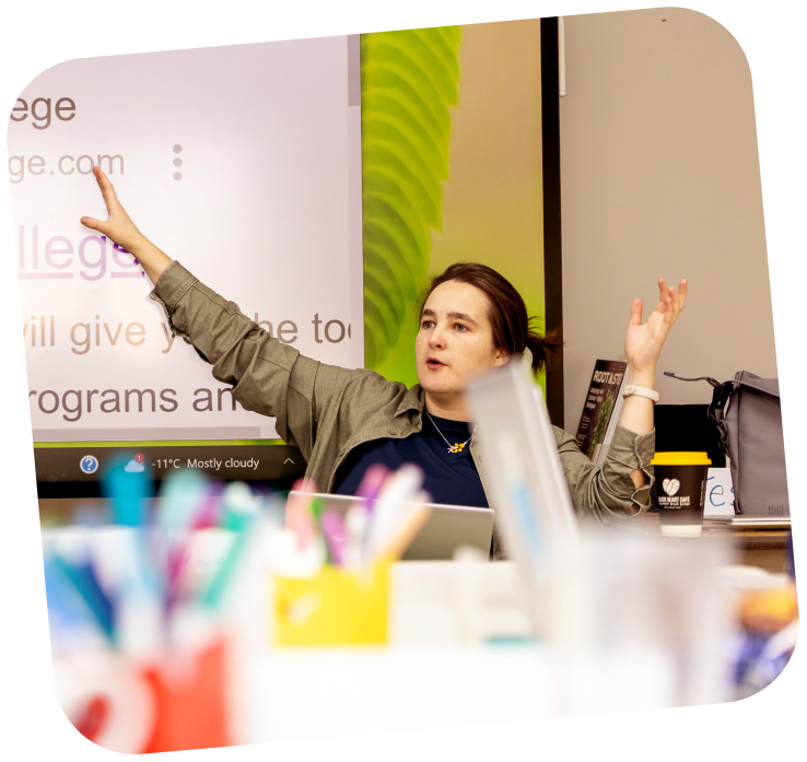 teens-presenter-digital-skills A STEAM educator with her hand raised and pointing towards a screen that is located behind her.