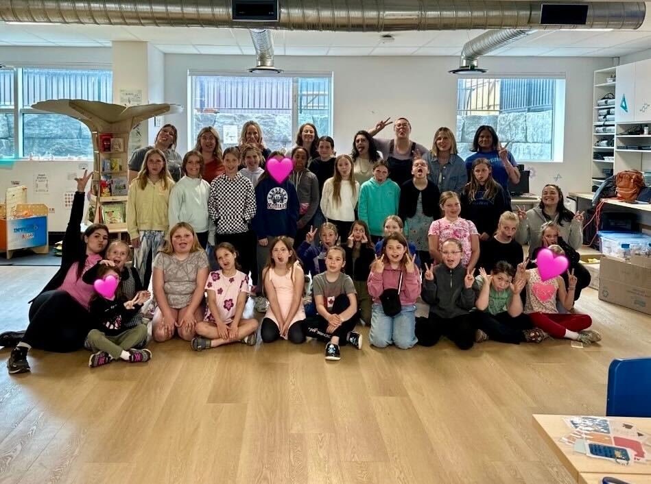A group of nearly 30 girls and non-binary youth pose for a group photo alongside nine women mentors.