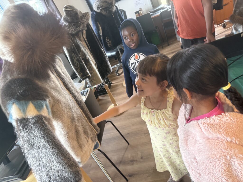 two children admire a seal skin fur coat on a stand in the Iqaluit Makerspace & Skills Hub