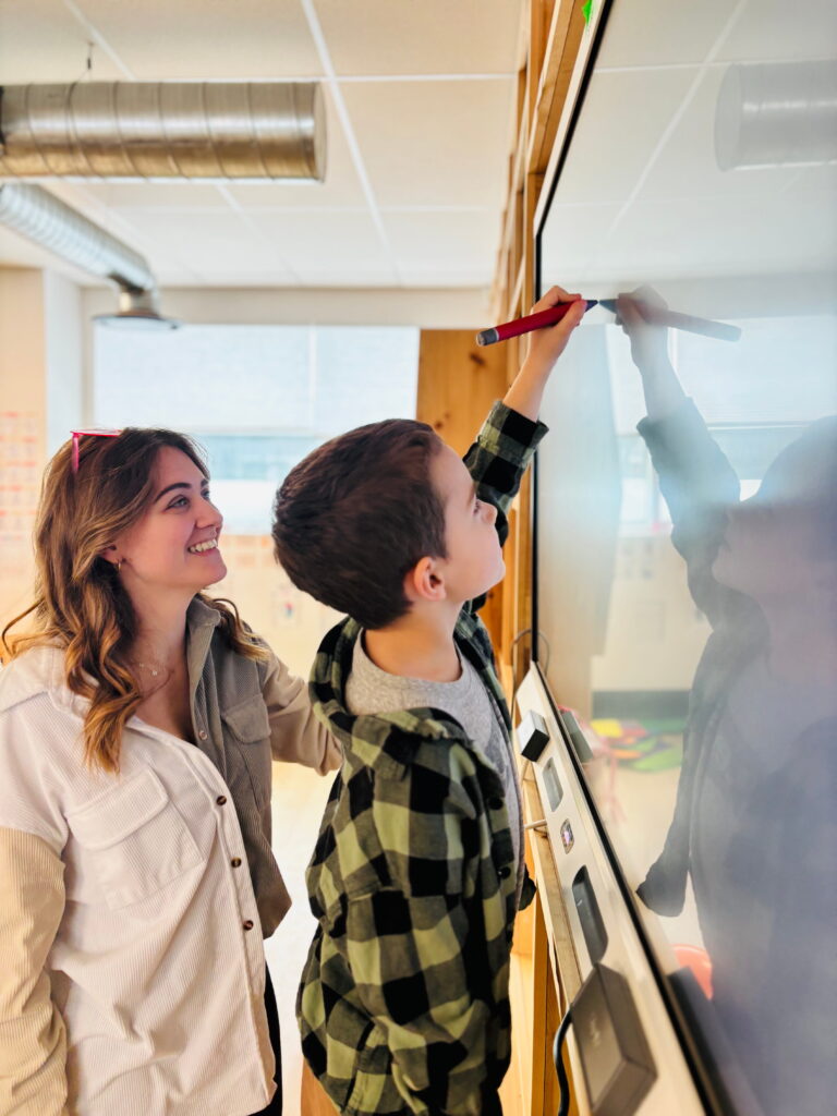 A child and a woman stand in front of a SMART Board at the Ampere Kawartha Lakes Makerspace and Skills Hub.