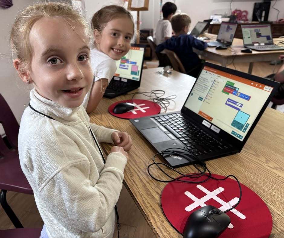 Children learning using a computer while seated at a table in the Bathurst Makerspace & Skills Hub